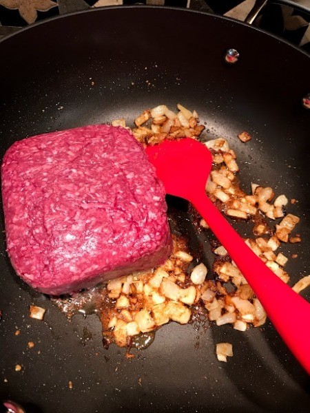 adding ground beef to seasoned onions