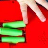 Child's hand putting batteries in a red toy.