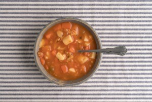 Bowl of soup on striped tablecloth.