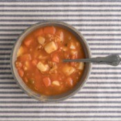 Bowl of soup on striped tablecloth.