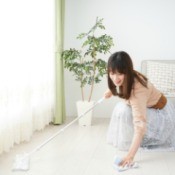 Woman cleaning floor near curtains.