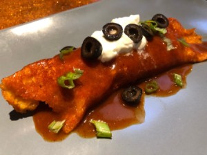 Cheese-Wrapped Chicken Enchilada on plate with sour cream & olives