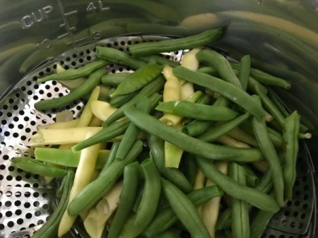 Fresh trimmed green beans inside the steamer basket.