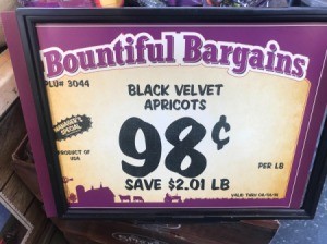 A price tag at a grocery store for apricots for 98 cents.