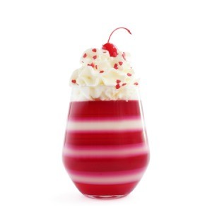 Layered jello in a glass with a cherry on top.