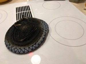 A burned hot pad next to a clean smooth top stove burner.