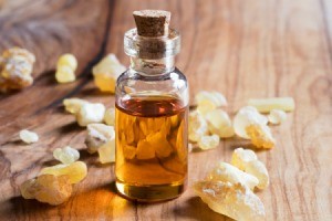 Bottle of essential oil on a wood table surrounded by amber.