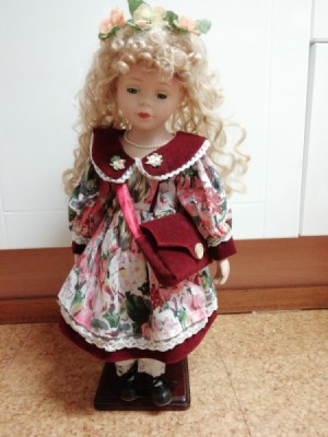 Identifying Porcelain Dolls - blonde doll wearing a floral dress with a red collar