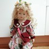 Identifying Porcelain Dolls - blonde doll wearing a floral dress with a red collar