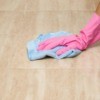Hand in pink glove wiping floor tiles.