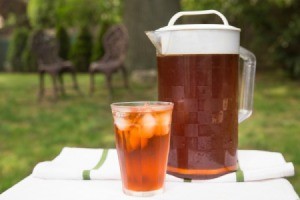 Pitcher and glass filled with ice tea on an outdoor table.