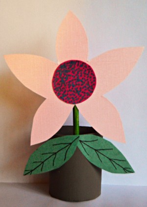 A decorative paper flower in a recycled toilet paper tube planter.
