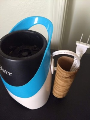 The cord to a small appliance placed inside a cord saver made from a hook and a cardboard toilet paper roll.