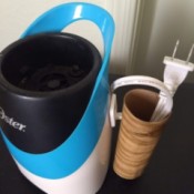 The cord to a small appliance placed inside a cord saver made from a hook and a cardboard toilet paper roll.