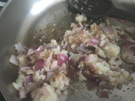 adding riced cauliflower and spices to onions