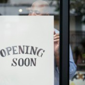 Man putting up an "opening soon" sign in a storefront.