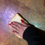 Using Bread to Pick Up Broken Glass - hand pressing a slice of bread onto a tile floor