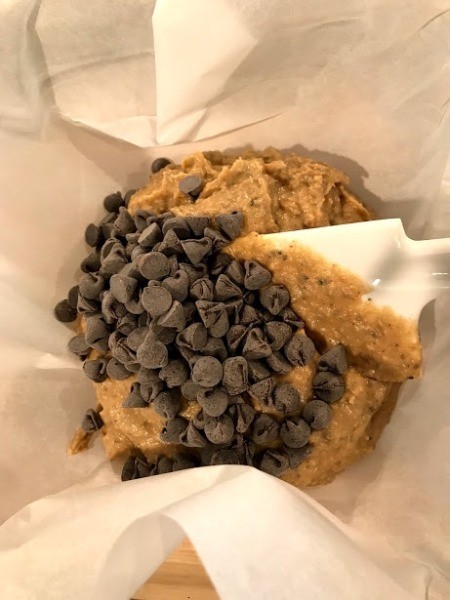 adding chips to batter on parchment paper