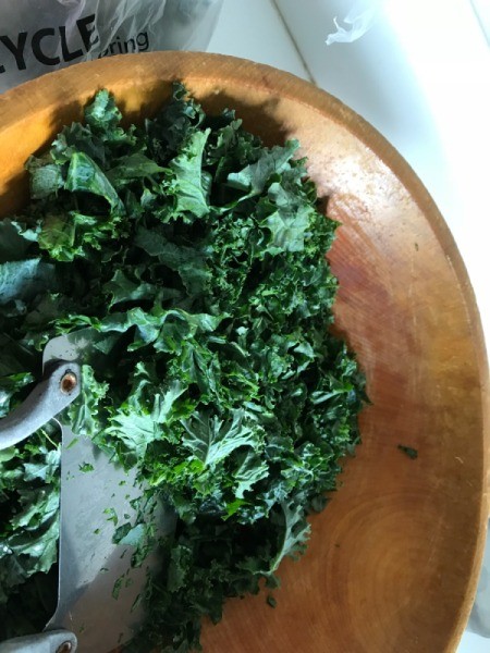 chopping kale in wooden bowl