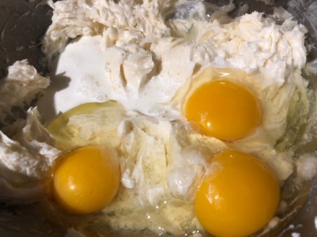 adding eggs to cream cheese and sugar