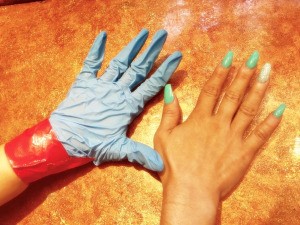 A manicured hand next to a gloved and duct-taped hand, protected from hair dye.