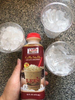 A bottle of Vietnamese coffee with three cups with ice.