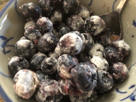 adding flour to blueberries