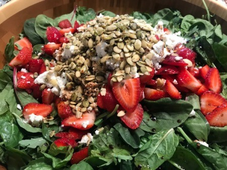 Strawberries, goat cheese, and pumpkin seeds added to greens