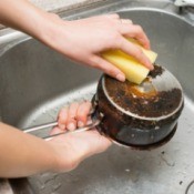 Washing a burnt pot in a sink.