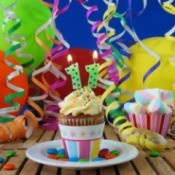 Cupcake with 11 candle surrounded by balloons and streamers.