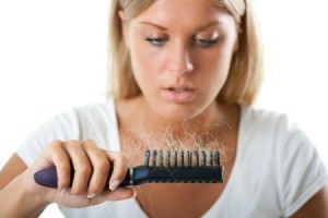 Woman looking at a brush full of hair.