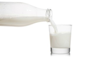 Glass milk bottle pouring a glass of milk.