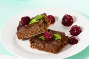 Pieces of fudge on a plate with cherries.