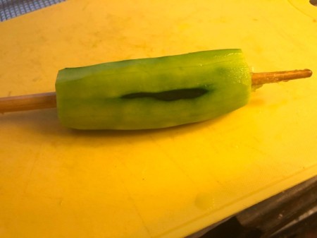 pushing chop stick threw peeled cucumber