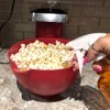 An oil spray being added to a bowl of popcorn.