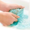 Hand washing a blue shirt in a sink.