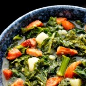 Kale soup with sausage and potato in a bowl.