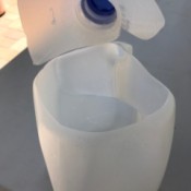 A milk jug with the top cut off for collecting water.