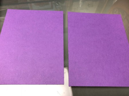 Two pieces of purple paper, to be used for a Halloween card.