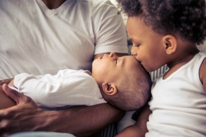 Young child kissing a newborn.