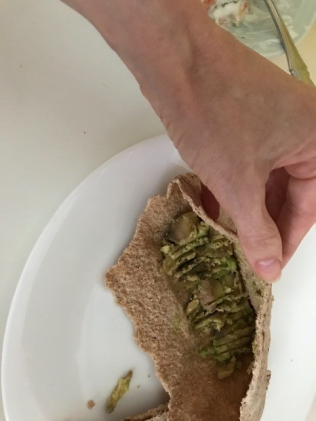 adding avocado to pita half