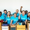 Group of volunteers in blue shirts with boxes of donations.