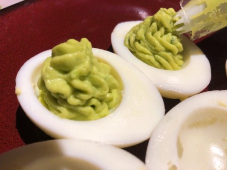 using piping tool to fill Guacamole Deviled Eggs