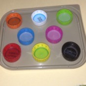 Repurpose Old Food and Storage Lids for Paint Palettes  - colored soda and water bottle caps on a squarish container lid as another option