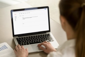 A woman writing an email on a laptop computer.