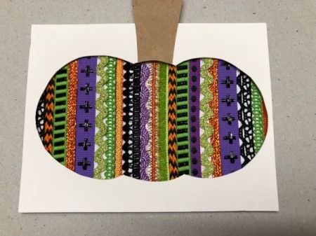 A step in making a Halloween card with a decorative pumpkin silhouette.