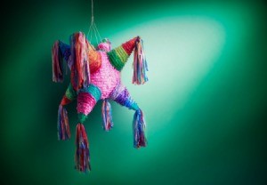 Piñata hanging in front of a green wall.