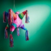 Piñata hanging in front of a green wall.