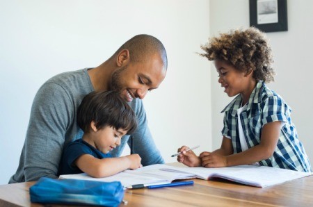 Father helping his sons with worksheets.