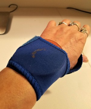 A wrist brace and a metal canning jar insert on a woman's wrist.